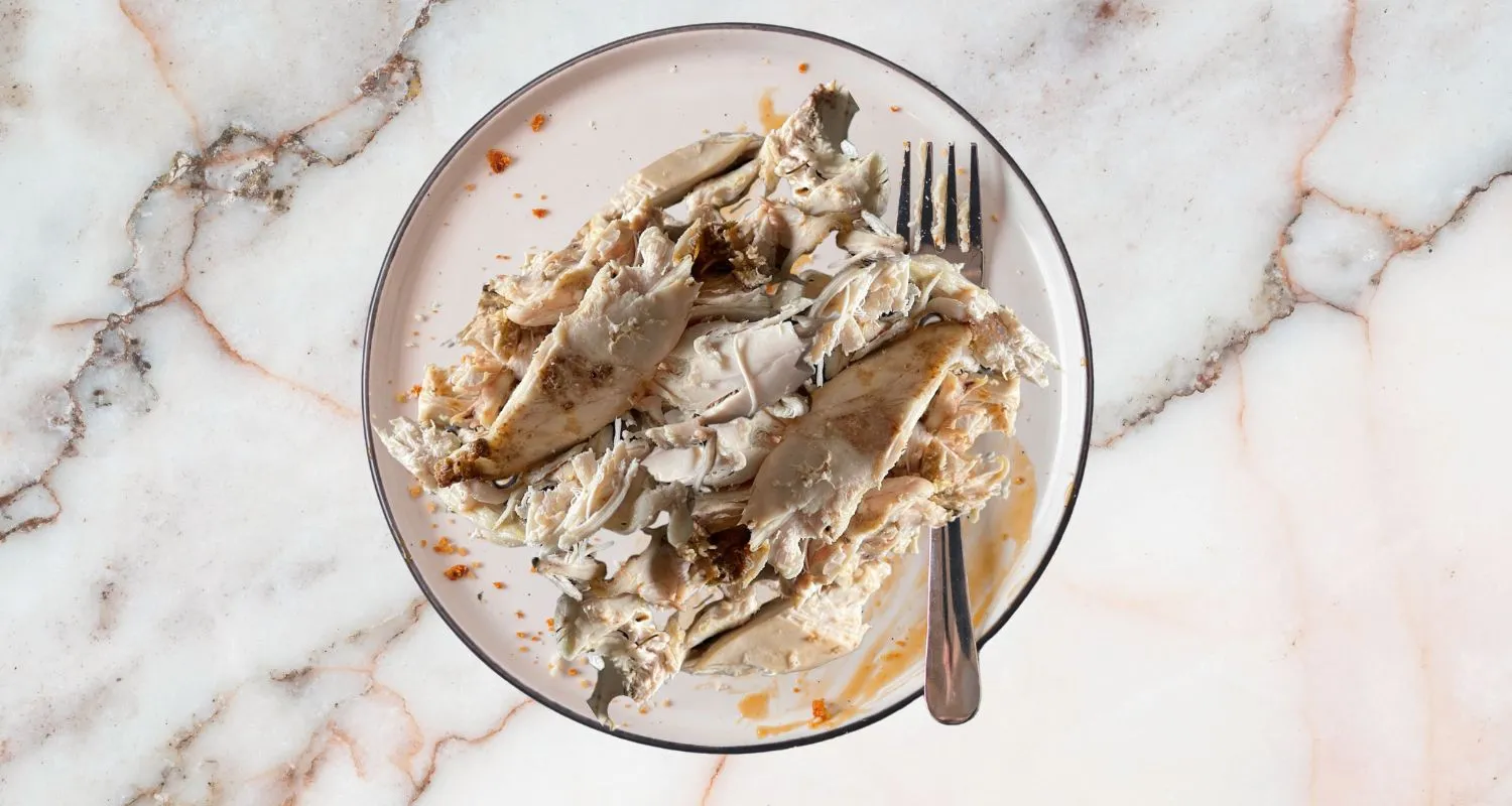 Shredded rotisserie chicken served on a glass plate with a fork, perfect for creating versatile leftover chicken recipes.