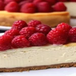 A creamy slice of homemade raspberry cheesecake with a golden crust and fresh raspberry topping.