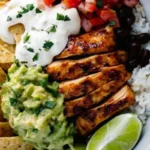 A close-up of honey chipotle chicken drizzled with sauce, served with cilantro-lime rice, guacamole, and sour cream.