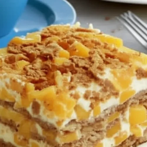 Mango float dessert featuring layers of whipped cream, graham crackers, and fresh mango chunks, topped with graham cracker crumbs.